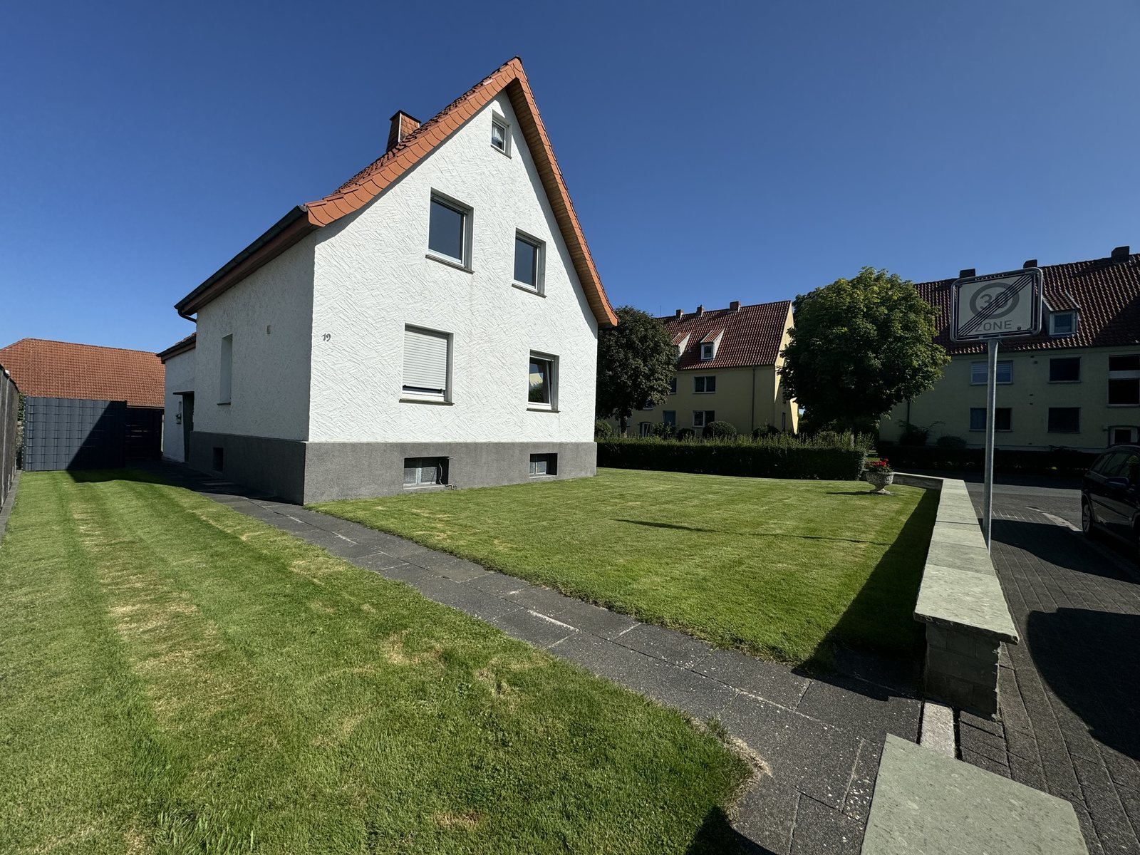 Verkauftes Einfamilienhaus mit großem Rasen bei blauem Himmel